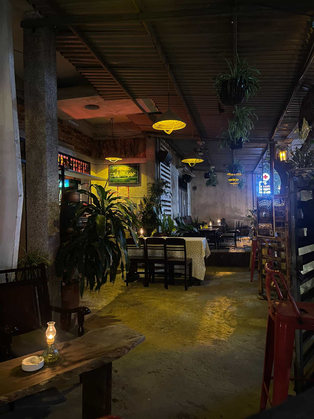 Wide interior at night with candle-lit tables and conical hat lamps